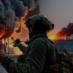 Український військовий спостерігає за боєм біля палаючого Кримського мосту