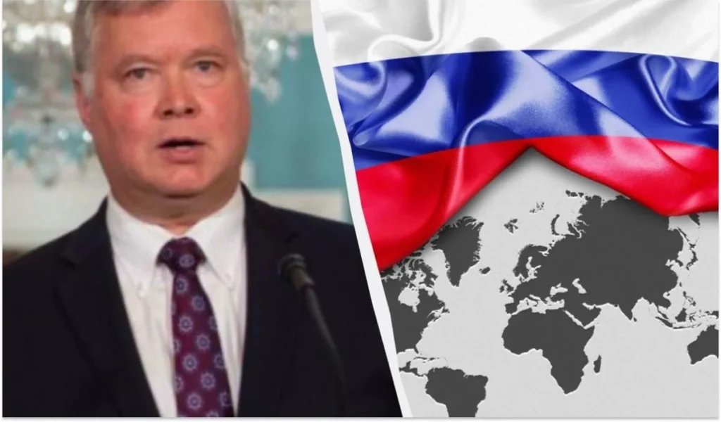 Екс-дипломат США Стівен Біґан на тлі прапора Росії та мапи світу