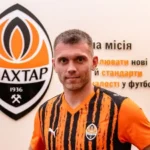 Олександр Караваєв у формі Шахтаря перед логотипом клубу