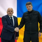 Польский и украинский чиновники жмут руки на фоне флагов Польши и Украины