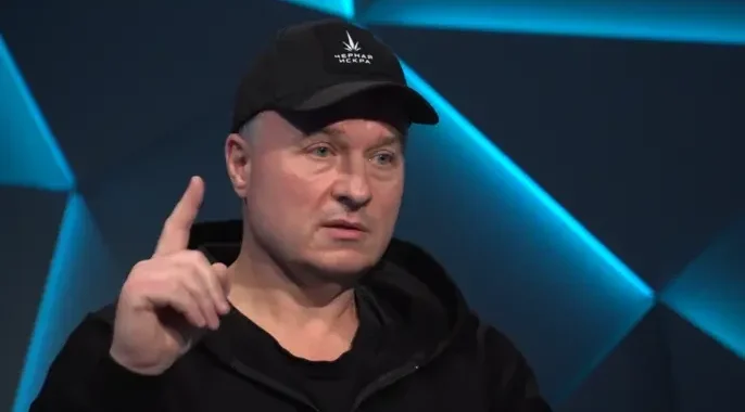 Активіст руху «Чорна іскра» в кепці з логотипом вказує пальцем