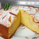 Пишний манник з яблуками з відрізаним шматком на тарілці