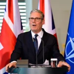 Кір Стармер виступає за трибуною з прапором НАТО