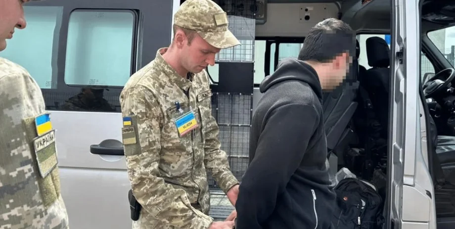 Військовослужбовець ТЦК у камуфляжі затримує чоловіка біля мікроавтобуса