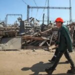 Робітник у касці йде серед руїн енерговузла Криму після ударів