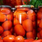Скляні банки з консервованими помідорами та свіжими овочами
