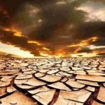 Потріскана висушена земля під хмарами екстремальної спеки 65°C