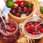 Банки вишневого варення зі свіжими вишнями та ложками на столі