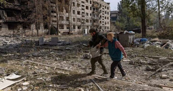 Военный сопровождает женщину среди руин разрушенной Константиновки