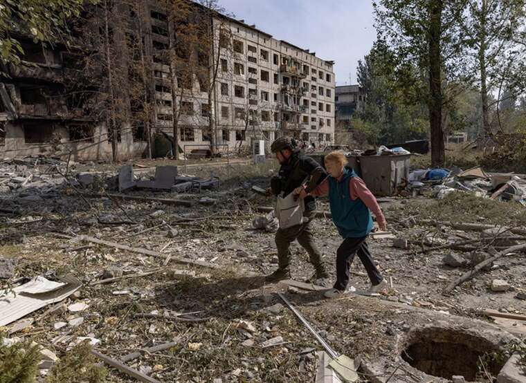 Военный сопровождает женщину среди руин разрушенной Константиновки