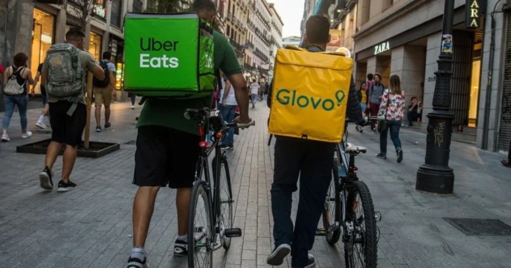 Курєри Uber Eats та Glovo з рюкзаками на вулиці після угоди Uber і Delivery Hero
