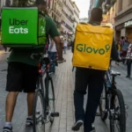 Курєри Uber Eats та Glovo з рюкзаками на вулиці після угоди Uber і Delivery Hero