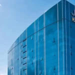 Сучасна скляна вежа ДТЕК на тлі блакитного неба