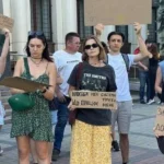 Молоді люди тримають картонні плакати біля колонади будівлі на протесті
