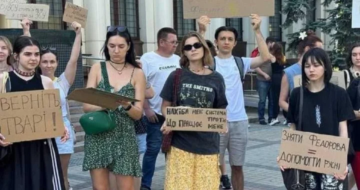Молоді люди тримають картонні плакати біля колонади будівлі на протесті