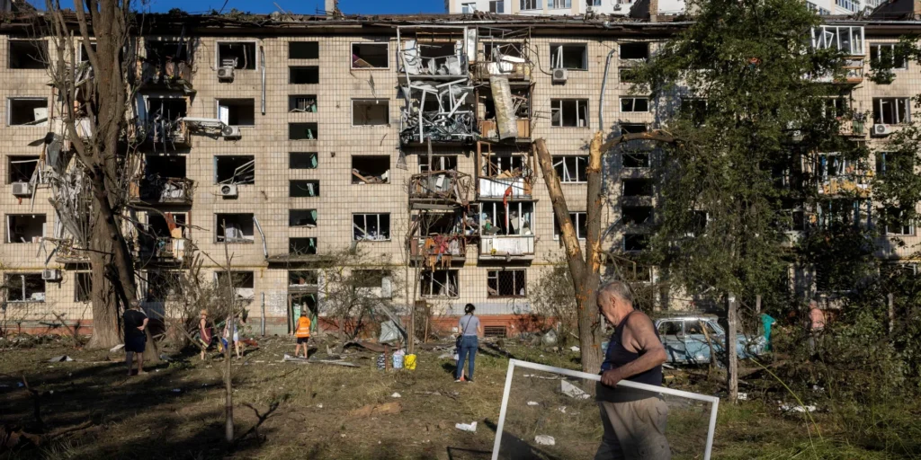 Зруйнована багатоповерхівка після обстрілу, люди серед уламків на подвір’ї