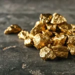 Купа золотих самородків на темній шорсткій кам’яній поверхні