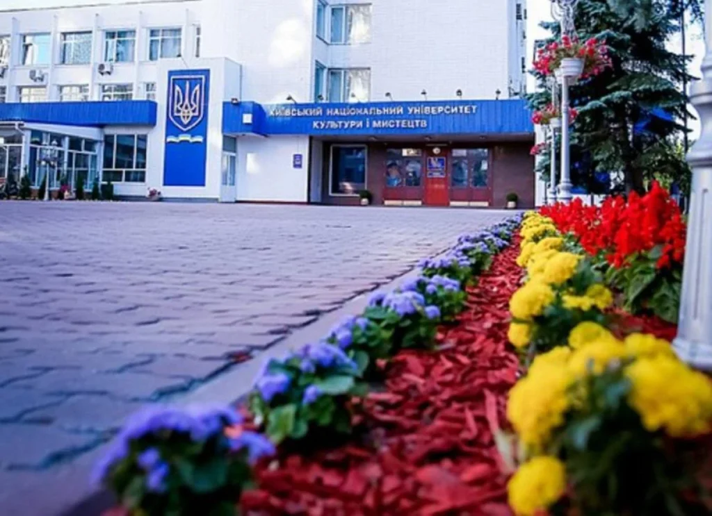 Головний корпус КНУКіМ з гербом України, вивіскою та квітниками перед входом