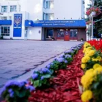 Головний корпус КНУКіМ з гербом України, вивіскою та квітниками перед входом