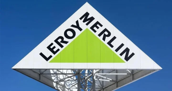 Біла трикутна вивіска Leroy Merlin із зеленим трикутником на тлі синього неба