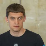 Іван Федоров у чорній футболці на тлі світлої камяної стіни