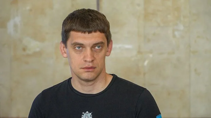 Іван Федоров у чорній футболці на тлі світлої камяної стіни