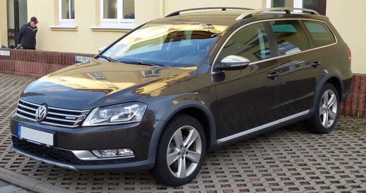 Темно-сірий універсал Volkswagen Passat Alltrack припаркований на бруківці біля жовтого будинку